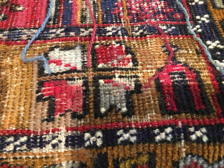 Restoration utilisant des brins de laine colorés pour raviver les motifs d'un tapis de laine fait main